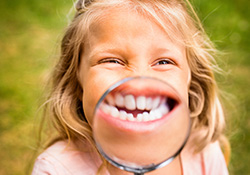 Little girl holding magnifying glass to smile